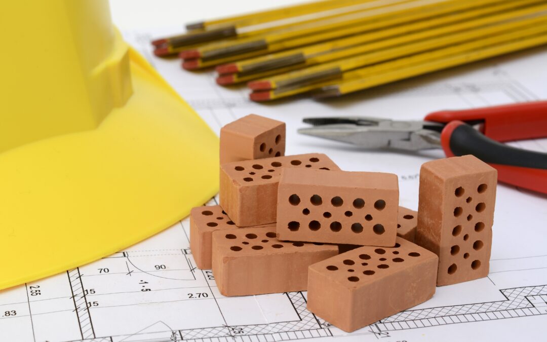 Plano de obra sobre mesa con ladrillos y lápiz, ilustrando proyectos y licencias en suelo rústico según la nueva Ley del Suelo de Canarias